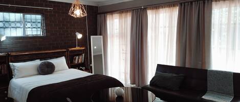 Une chambre d’hôtel avec un lit, un canapé, une petite table et un miroir.