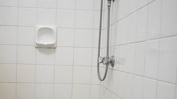 A small, tiled shower area with a handheld showerhead and two wall-mounted urinals.