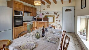 A kitchen with wooden cabinets, a dining table set for four, and a stone wall.