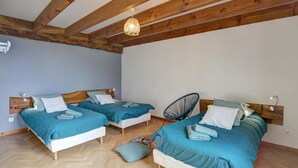 A room with two beds, wooden beams on the ceiling, and a hanging light fixture.