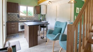 A modern kitchen with wooden cabinets, a central island, and a bar stool. - Cozy House in Périgord Noir with Garden (Cénac-et-Saint-Julien)