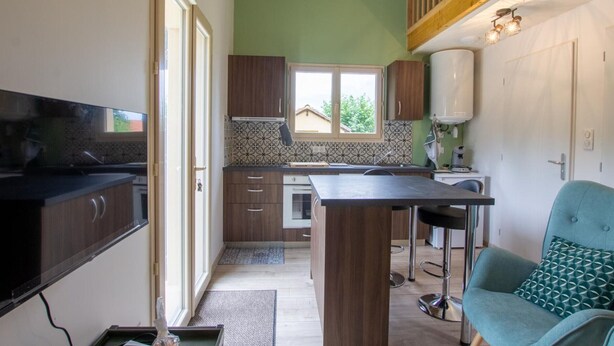 A compact kitchen with a central island, wooden cabinets, and a view to the outside. - Cozy House in Périgord Noir with Garden (Cénac-et-Saint-Julien)
