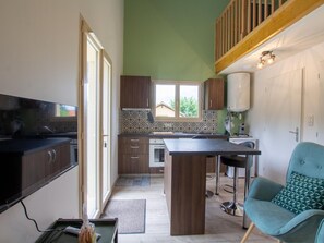 A compact kitchen with a central island, wooden cabinets, and a view to the outside.
