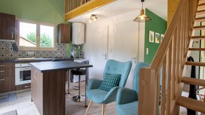 A modern kitchen with a central island, bar stools, and a staircase with wooden railings. - Cozy House in Périgord Noir with Garden (Cénac-et-Saint-Julien)