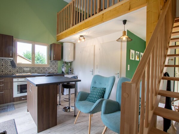 A modern kitchen with a central island, bar stools, and a staircase with wooden railings.