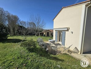 A house with a patio, a small shed, and a garden with grass and trees.