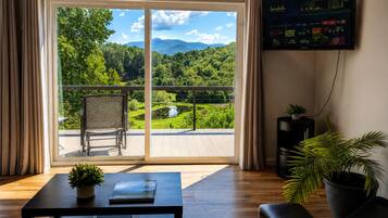 Ein Zimmer mit einer großen Schiebeglasdoor, die auf einen Balkon mit Blick auf eine Berglandschaft führt.