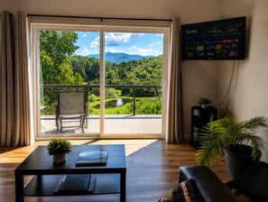 Una habitación con un gran ventanal corredera que da a un balcón con vistas a un paisaje montañoso.