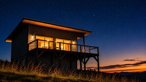 Uma cabana de madeira com varanda, sob um céu estrelado.