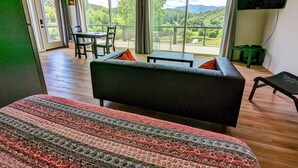 Una habitación amplia con una cama grande, un sofá y un comedor con vistas a un paisaje exuberante.