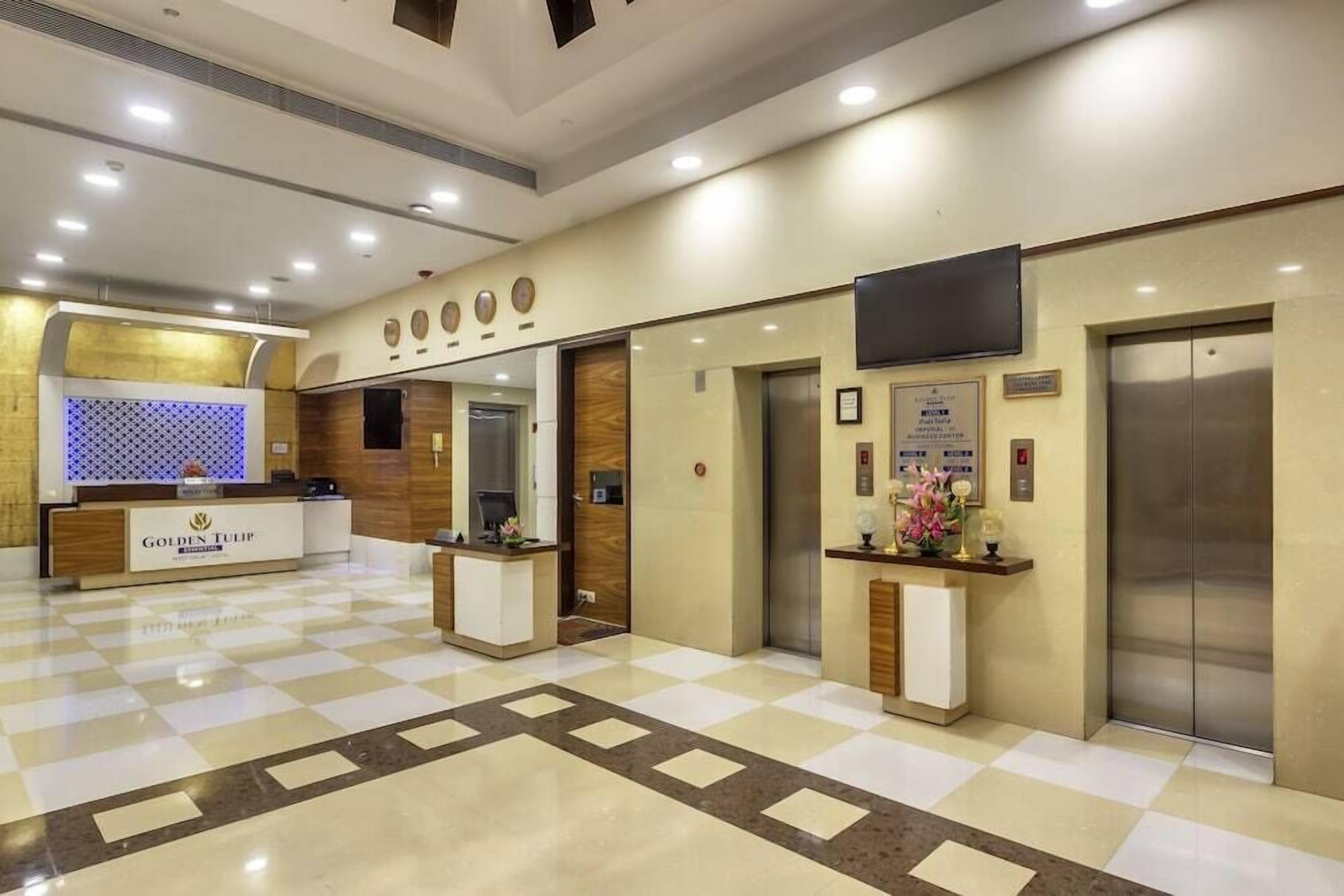 A hotel reception area with a check-in counter, reception desk, and a reception area with a flat-screen TV mounted on the wall.