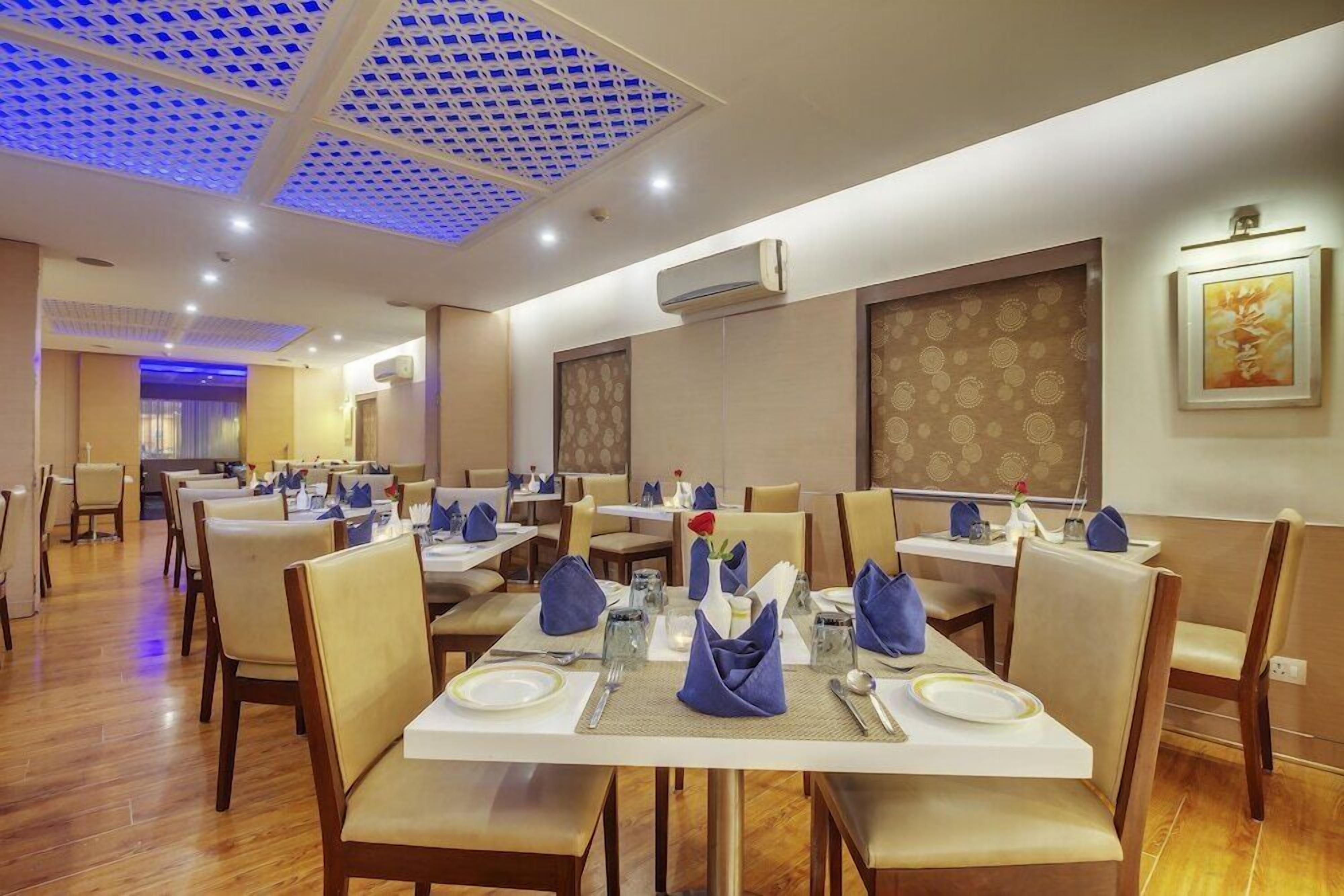A restaurant with multiple tables, chairs, and a ceiling with a blue pattern.