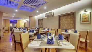 A restaurant with multiple tables, chairs, and a ceiling with a blue pattern.