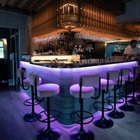 A bar area with a curved counter, bar stools, and a bartender.