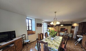 A kitchen with a dining table, chairs, a TV, and a chandelier.