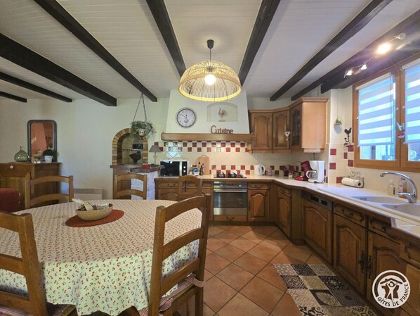 Une cuisine chaleureuse avec des meubles en bois, un dosseret carrelé et un luminaire suspendu.
