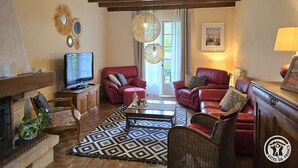 A living room with a fireplace, two red leather sofas, a television, and a patterned rug. - Birdsong: Private Pool, Wifi, Pets Welcome, Garden (Chancelade)