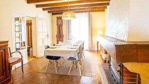 A dining room with a long table set for six, wooden beams on the ceiling, a large clock, and a fireplace. - Birdsong: Private Pool, Wifi, Pets Welcome, Garden (Chancelade)