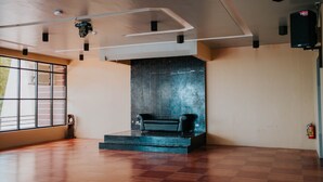 A spacious room with a large window, a black sofa on a platform, and a fire extinguisher on the wall. - 4k's Pension House by Cocotel (Bogo)
