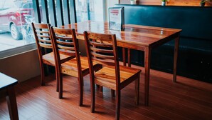 A wooden table and chairs in a restaurant with a view of the street outside. - 4k's Pension House by Cocotel (Bogo)