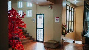 A hotel lobby with a wooden floor, a staircase, a fire exit door, and a sign indicating a smoking area. - 4k's Pension House by Cocotel (Bogo)