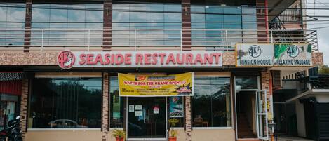 Un restaurante con un letrero que dice "4K SEASIDE RESTAURANT" y un banner anunciando su gran inauguración.