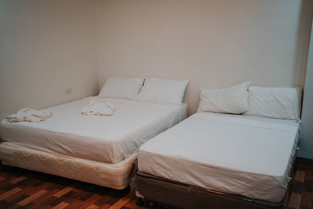 Deux lits simples avec du linge de lit blanc et un plancher en bois.