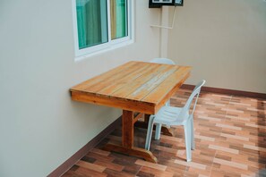 A wooden table with a white chair in a room with a tiled floor and a window with curtains. - 4k's Pension House by Cocotel (Bogo)