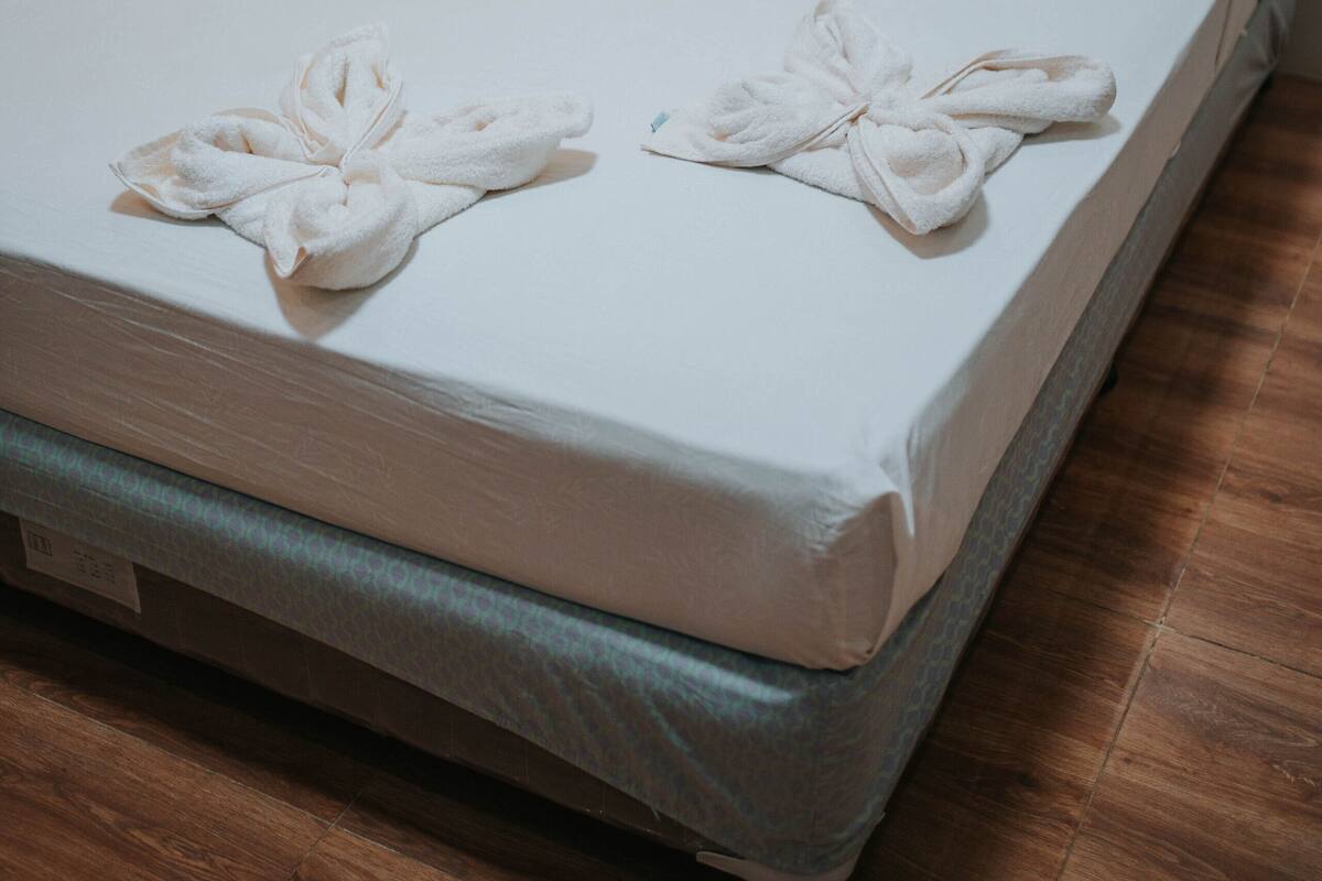 Un lit bien fait, avec deux serviettes pliées en forme de nœuds posées sur le couvre-lit.