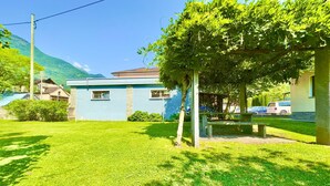 En bostadsfastighet med en välskött gräsmatta, en liten trädgård och ett hus med en blå fasad.