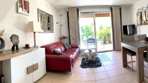 A compact living space with a red sofa, a dining table, and a TV. - SUPERB VILLA 80 m2 in DUPLEX, 6 pers, 3 bedrooms, 2 bathrooms + garage and garden (Agde)