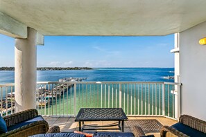 Un balcon avec vue sur la mer, une table et des meubles en osier.
