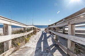 A wooden boardwalk leading to a beach with clear skies.