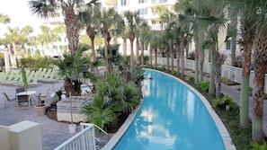 A pool area with palm trees, lounge chairs, and a building in the background.