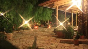 A stone-paved courtyard with potted plants and a wooden pergola structure. - Townhome (Cefalù)
