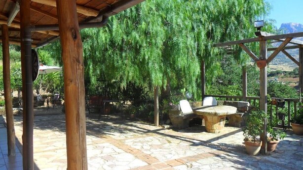 A covered outdoor area with stone flooring, wooden pillars, and seating arrangements. - Townhome (Cefalù)