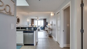 A spacious kitchen with a central island, a dining area with a chandelier, and a view to a balcony. - Ariel Dunes I 508 * Beachy* Modern* 3 pools* (Miramar Beach)