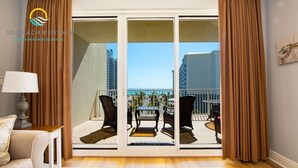 A balcony with a view of the beach and buildings, furnished with chairs and a table. - Ariel Dunes I 508 * Beachy* Modern* 3 pools* (Miramar Beach)