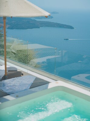 A pool with a view of the sea and distant islands. - Anemos Cave Suites (Santorini)