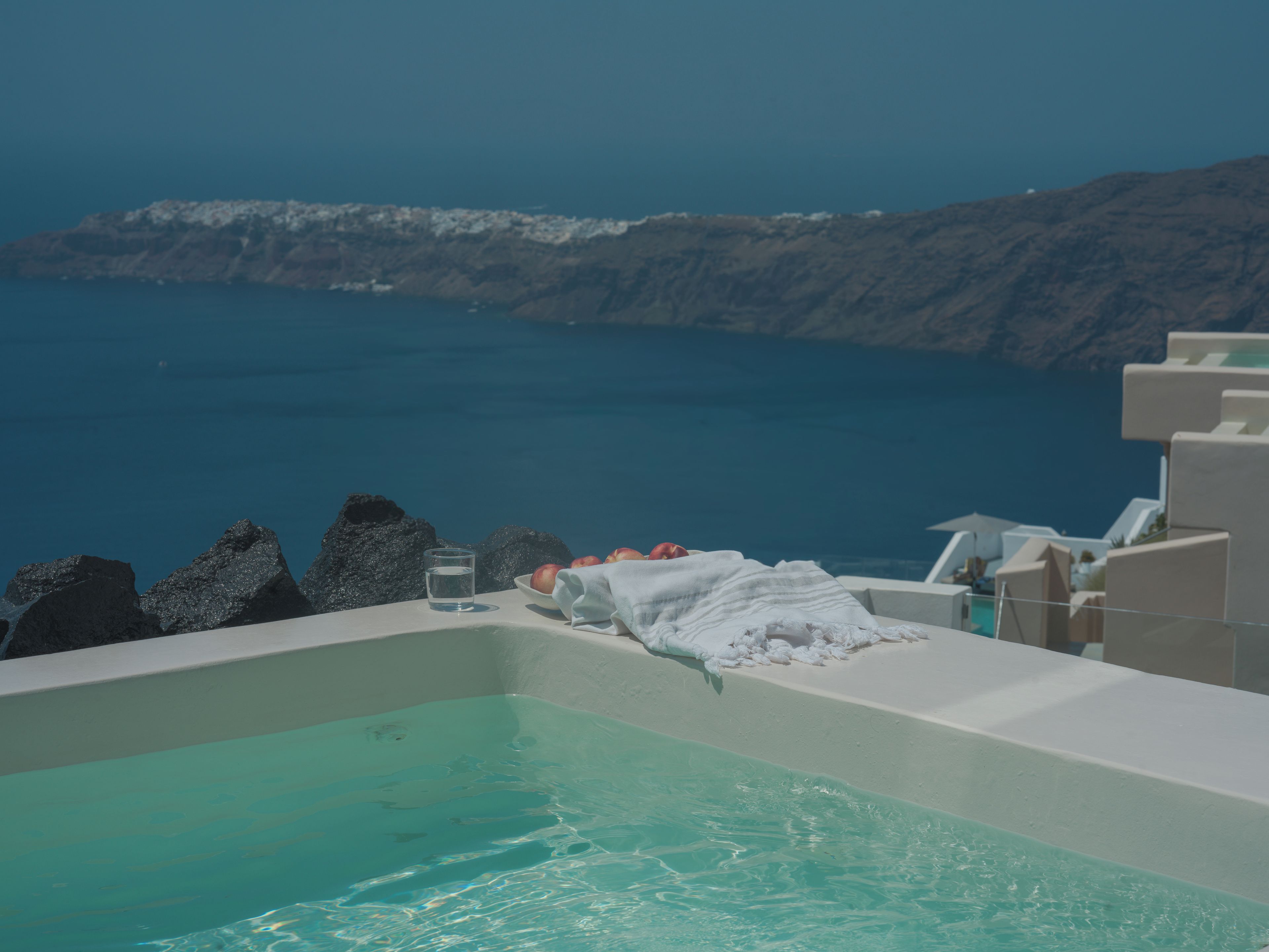 A bathtub with a view of the sea and rocky terrain.