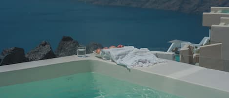 A bathtub with a view of the sea and rocky terrain.