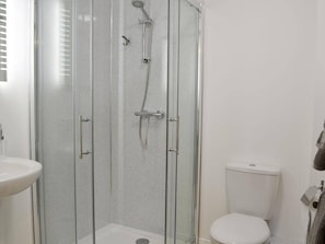 A glass-enclosed shower stall with a toilet and sink in a bathroom. - Stylish 3-bed Cottage Located in the Cairngorms (Ballindalloch)