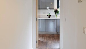 Eine moderne Küche mit Glastür, einer Arbeitsplatte mit Vase und Flasche, sowie einem Holzboden.