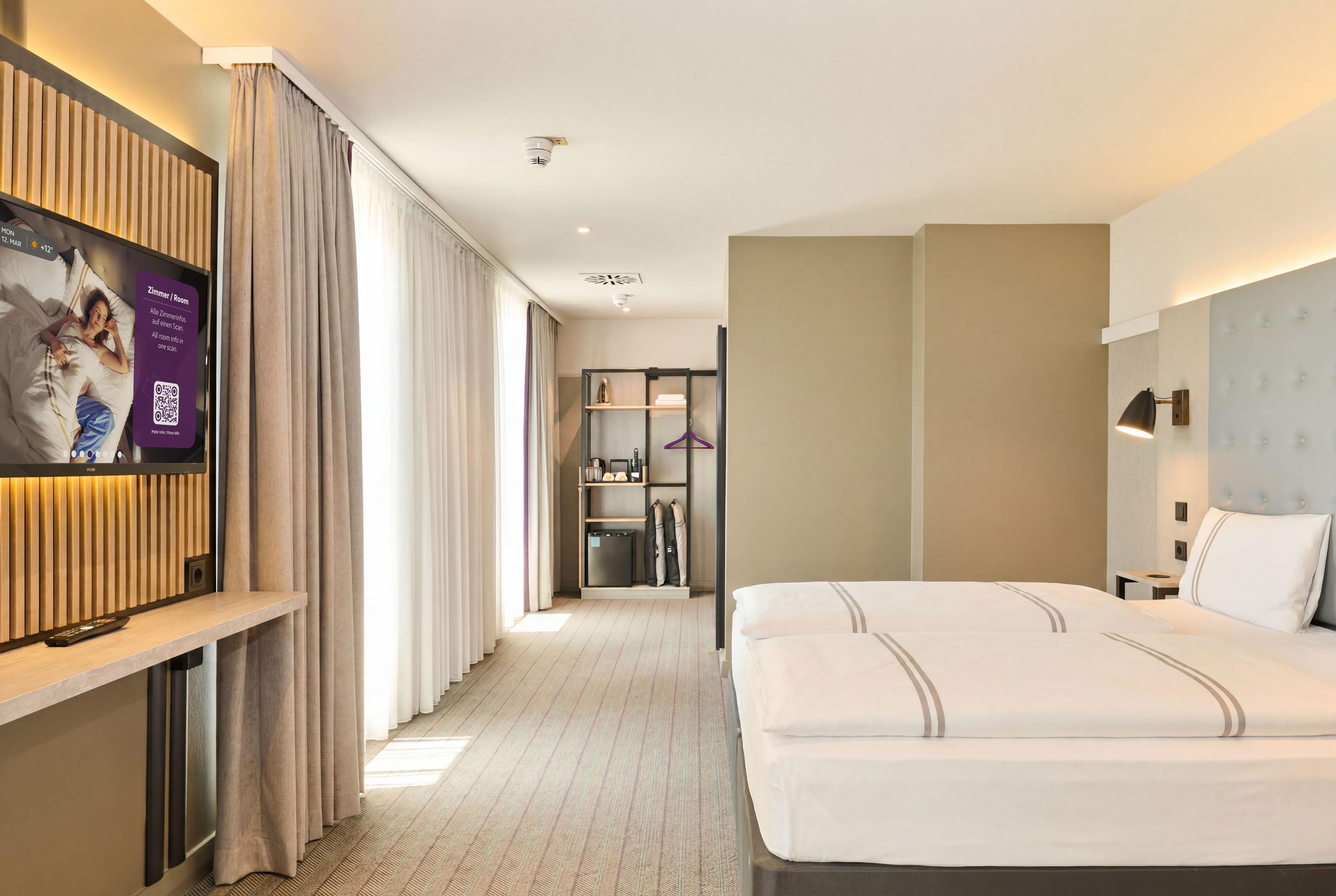 A hotel room with a bed, a TV, a wardrobe, and a bathroom.