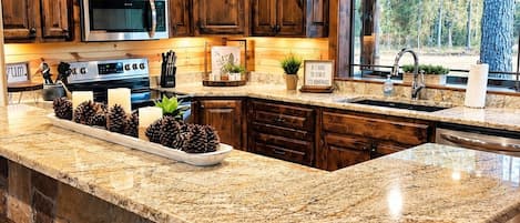 A kitchen with wooden cabinets, a granite countertop, a built-in oven, and a large island with bar stools.