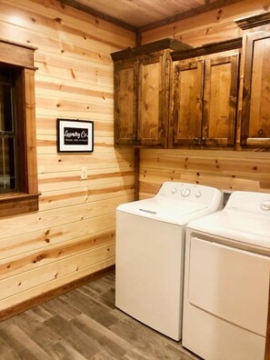 A laundry room with wooden walls and cabinets, a washing machine, and a dryer.