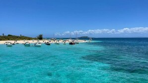 A beach with clear turquoise water, boats, and a sandy shore. - Luxury Italian Megayacht (Fajardo)