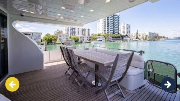 A boat deck with a table and chairs, a view of the water, and high-rise buildings in the background. - Luxury Italian Megayacht (Fajardo)