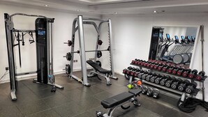 Ein Fitnessraum mit Krafttrainingsgeräten, Bänken und Kurzhanteln.