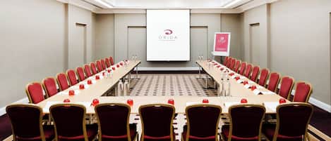 A conference room with a long table, red chairs, and a projector screen displaying the ORIDA logo.